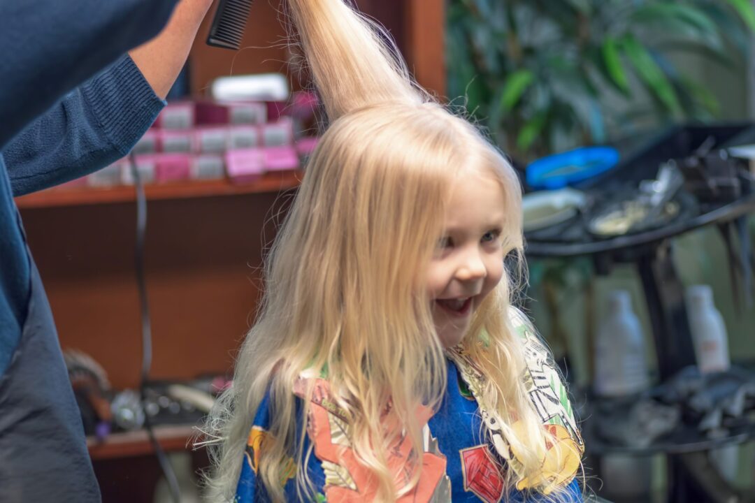 Little girl with long blonde hair getting first haircut